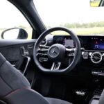 Widok na kierownicę i ekrany sterowania zza foteli przednich w samochodzie mercedes-Benz Klasa A