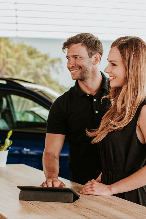 Uśmiechnięta para stoi przy biurku w salonie Mercedes-Benz, rozważając zakup