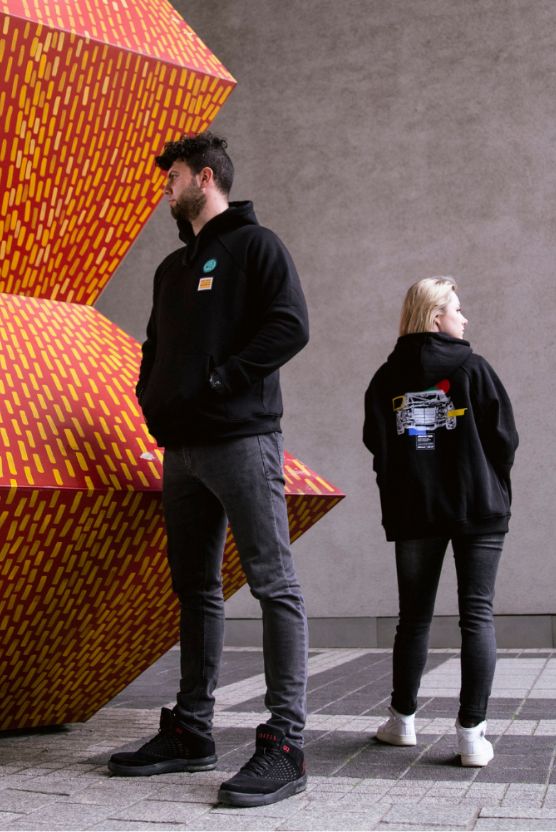 Dwie osoby w ubraniach z kolekcji #KochamyMercedesy obserwują miejską instalację artystyczną